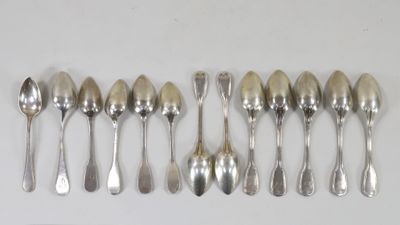 six cuillères en argent sont alignées sur une surface blanche