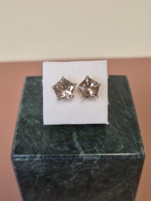 a close up of a pair of earrings sitting on top of a marble block