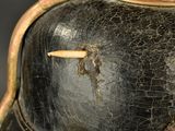 a close up of a black vase with a gold decoration on it
