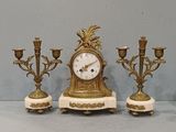 trois bougies et une horloge posées sur une table
