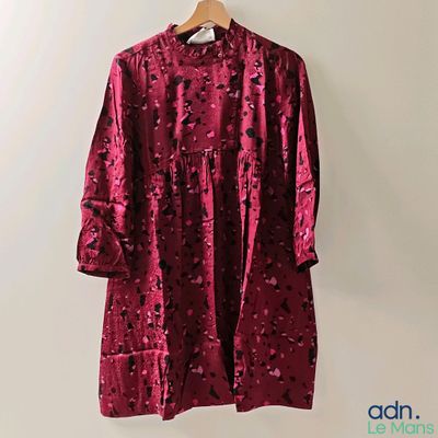 un manteau en velours violet orné de fleurs noires, suspendu à un cintre
