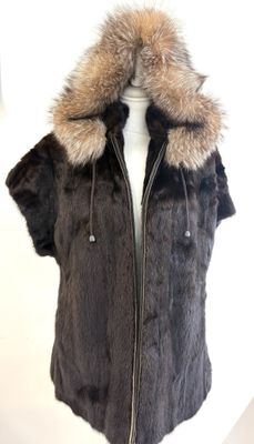 La veste est en fourrure et possède une capuche avec un col en fourrure.