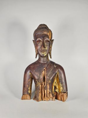 une vieille statue en bois représentant un Bouddha assis sur une surface blanche