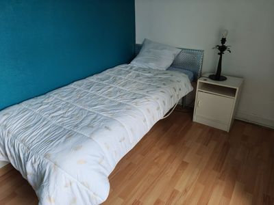a bed with a white comforter and a blue wall