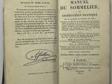 un livre ouvert, sur lequel figure une signature, posé sur une table
