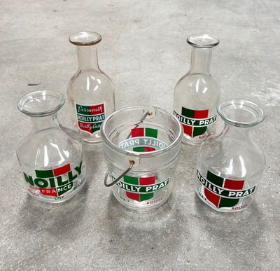 Des bouteilles de différentes tailles et couleurs sont alignées sur une surface en béton