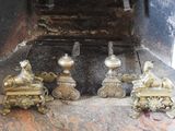 four brass figurines sitting in front of a fire place