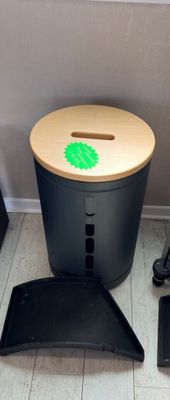 a black trash can with a green sticker on it next to a laptop