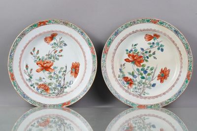 Deux assiettes ornées de fleurs et de feuilles sont posées sur une table.