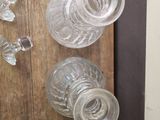 several empty glass vases sitting on a wooden shelf