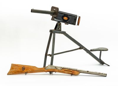 un vieux pistolet et un fusil posés sur un trépied, devant un fond blanc