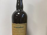 une bouteille de vin posée sur une table en bois, avec un mur blanc en arrière-plan