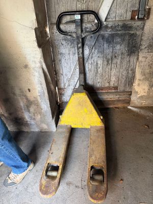 a man standing next to a fork lifter in a garage