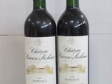 two bottles of wine sitting next to each other on a counter
