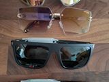trois paires de lunettes de soleil à verres miroirs posées sur un support en bois