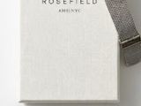 a white watch sitting on top of a book with a silver band