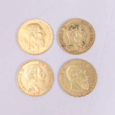 quatre types différents de pièces d'or reposant sur une surface blanche