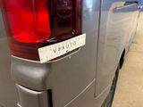 the rear end of a silver van with a sticker on it ' s tail light
