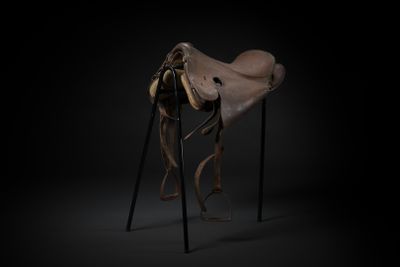 an image of a horse ' s saddle on a stand in the dark