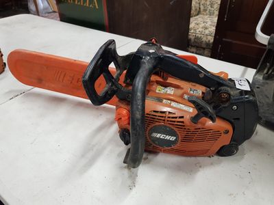an orange and black chainsaw sitting on top of a white table