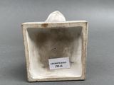 porcelain figurine of a man in a square box with a label on it
