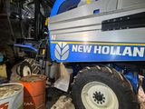 a blue and white new holland combiner parked in a garage