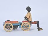 toy figurine of a man sitting on a cart of fruit