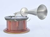 une enceinte argentée et rouge posée sur un socle en bois