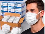 a man wearing a face mask next to a box of face masks