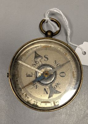 une petite boussole en or munie d'une étiquette