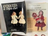 several antique dolls and books are on a table