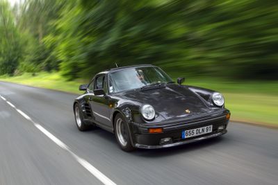 blurry photograph of a black sports car driving down a country road