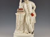statue représentant un homme assis à un bureau sur lequel se trouve un livre