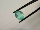 a close up of a pair of tongs holding an emerald stone