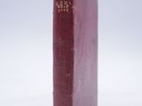 an old red book sitting on top of a white surface