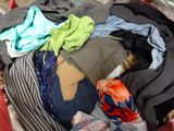 a pile of clothes sitting in a suitcase on the floor