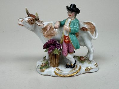 une figurine représentant un homme chevauchant une vache, avec un panier de fleurs