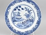 blue and white plate with a landscape scene on it
