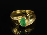 a close up of a gold ring with a green stone