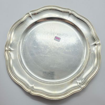 une assiette en argent posée sur une table blanche, sur laquelle est collé un autocollant rose
