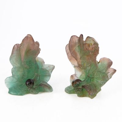 two figurines of leaves on a white surface
