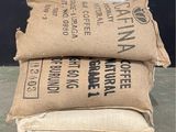 three bags of coffee sit on a pallet in front of a black wall
