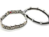 pair of stainless steel bracelets with red stones on white background