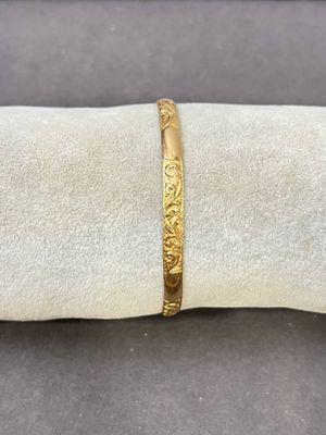 un gros plan d'un bracelet en or posé sur une serviette