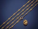a close up of a gold chain with a heart charm on it
