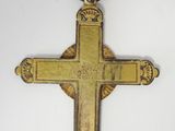 an old gold cross is hanging on a white wall