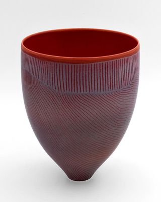 un gros plan d'un bol rouge posé sur une surface blanche