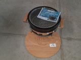 un petit barbecue posé sur un support en bois au sol