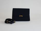 un petit sac à main noir avec un fermoir doré et une ceinture noire