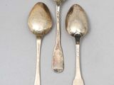 three silver spoons and two silver spoons sitting on a table